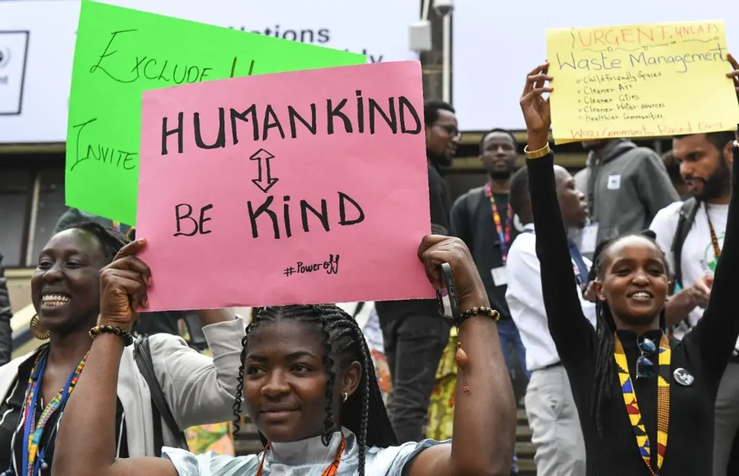 A group holds handwritten placards, including one reading Humankind, Be Kind.