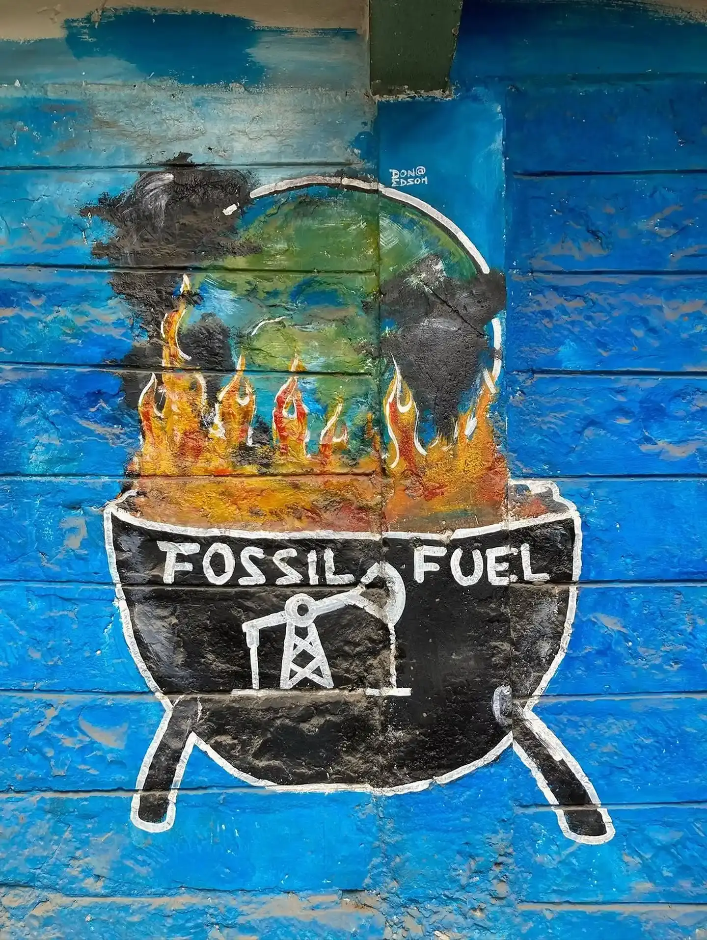 A mural shows the Earth burning above a barbecue marked Fossil Fuel.